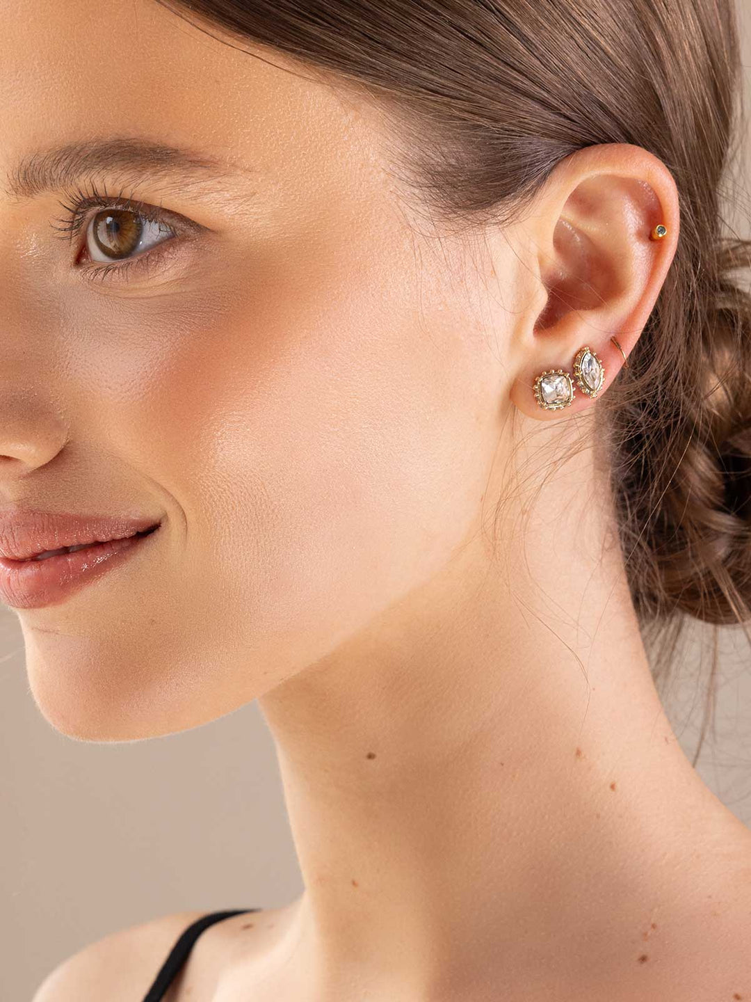 Close-up of a woman wearing a set of earrings with a neutral background